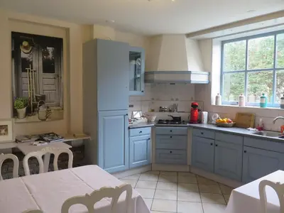 a kitchen with blue cabinets and a table with chairs at Café Brasserie Het Heerenhuis in Het Kalf