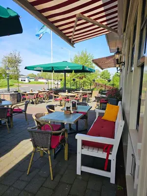 an outdoor patio with tables and chairs and umbrellas at Café Brasserie Het Heerenhuis in Het Kalf