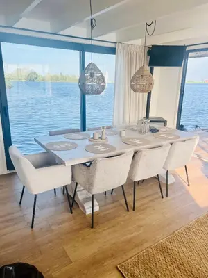 a dining room table with chairs and a view of the water at Surla houseboat 