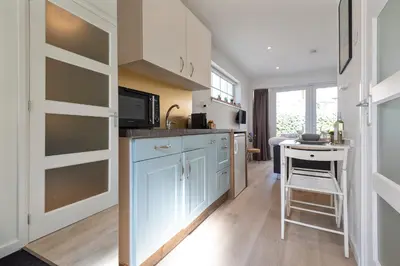 a kitchen with white cabinets and a small table at Forest and Ocean in Zandvoort