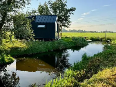 a tiny house on the side of a river at TinyHouse Noorderlicht in Haastrecht