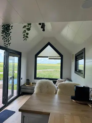 a living room with a table and chairs and a window at TinyHouse Noorderlicht in Haastrecht