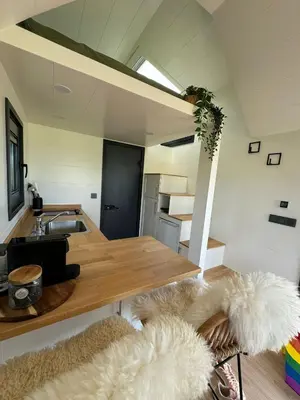 a kitchen with a sink and a table with furry rugs at TinyHouse Noorderlicht in Haastrecht