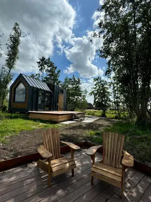 two chairs on a deck with a tiny house at TinyHouse Noorderlicht in Haastrecht