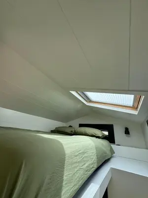 a bedroom with a bed and a skylight in the ceiling at TinyHouse Noorderlicht in Haastrecht