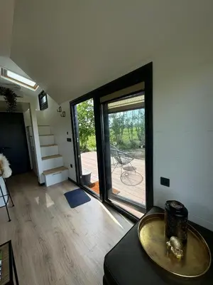 a living room with a table and a large glass door at TinyHouse Noorderlicht in Haastrecht