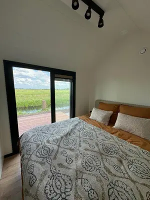 a bedroom with a large bed with a large window at TinyHouse Ochtendgloren in Haastrecht