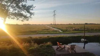 two chairs and a table on a boardwalk in a field at TinyHouse Ochtendgloren in Haastrecht
