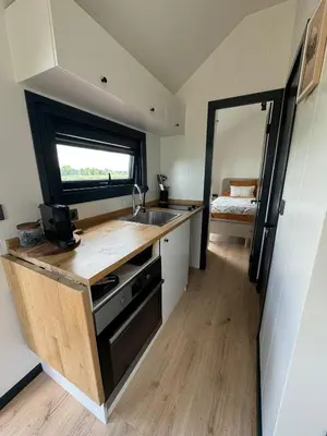 a small kitchen with a sink and a window at TinyHouse Ochtendgloren in Haastrecht