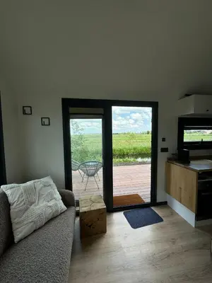a living room with a couch and a sliding glass door at TinyHouse Ochtendgloren in Haastrecht