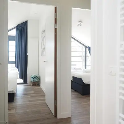 a bedroom with a bed and a room with a mirror at Villa Zon & Duin in Egmond aan den Hoef