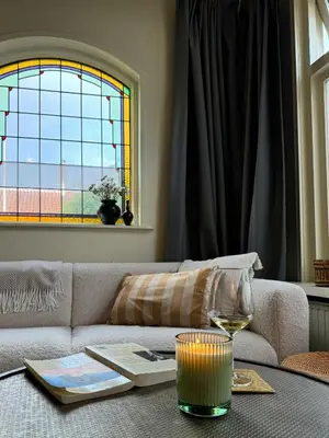 a living room with a couch and a glass of wine at Sunny Side Up in Egmond aan Zee