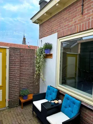 a patio with two chairs and a couch and a window at Sunny Side Up in Egmond aan Zee