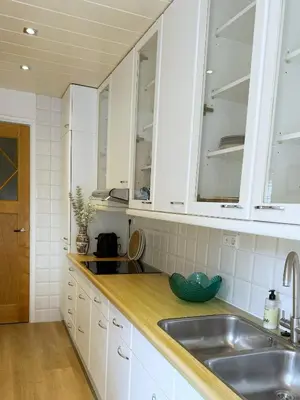 a kitchen with white cabinets and a sink at Sunny Side Up in Egmond aan Zee
