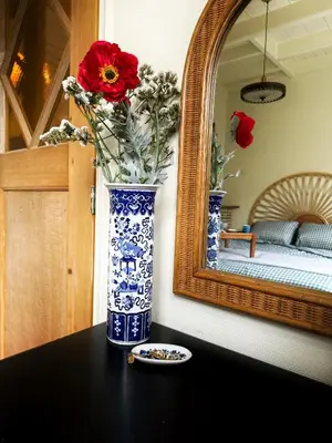 a blue and white vase with flowers on a table in front of a mirror at Sunny Side Up in Egmond aan Zee