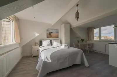 a bedroom with a large white bed in a attic at Strandhuis 122 Studio in Egmond aan Zee