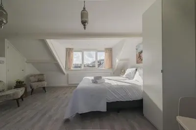 a white bedroom with a bed and a window at Strandhuis 122 Studio in Egmond aan Zee