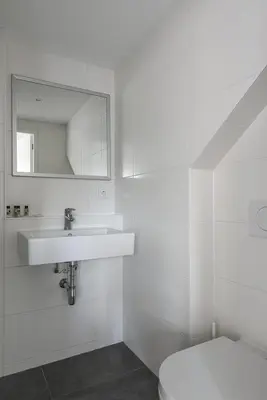 a white bathroom with a sink and a toilet at Strandhuis 122 Studio in Egmond aan Zee