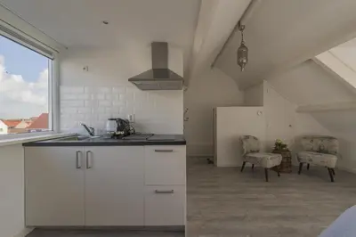 a kitchen with white cabinets and a sink and a window at Strandhuis 122 Studio in Egmond aan Zee