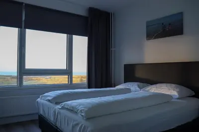 two beds in a room with two large windows at Sea la Vie in Egmond aan Zee