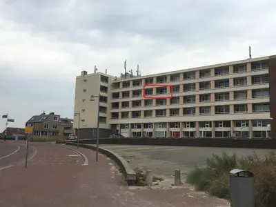 a building with a red sign on the side of it at het Zeehuisje in Egmond aan Zee