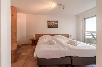 a bedroom with a bed with white sheets and a window at Atlantis 14b in Egmond aan Zee