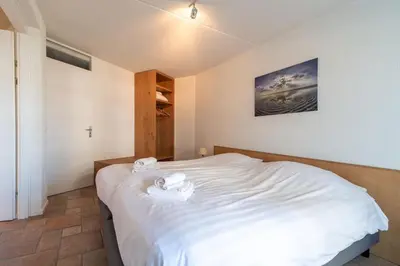 a bedroom with a white bed with two towels on it at Atlantis 14b in Egmond aan Zee