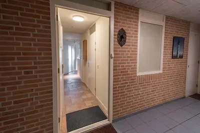 a hallway with a brick wall and an open door at Atlantis 14b in Egmond aan Zee