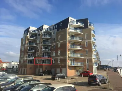 a tall building with cars parked in a parking lot at Atlantis 14b in Egmond aan Zee