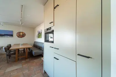 a kitchen and dining room with white cabinets and a table at Atlantis 14b in Egmond aan Zee