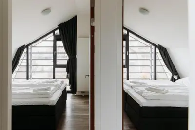 two beds in a room with two windows at Villa Duinhuis Zee in Egmond aan den Hoef