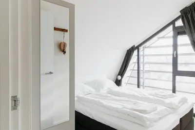 a white bed in a room with a window at Villa Duinhuis Zee in Egmond aan den Hoef