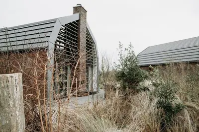 an old brick building in the middle of a field at Villa Duinhuis Zee in Egmond aan den Hoef
