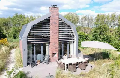 a brick building with a table and an umbrella at Villa Duinhuis Zee in Egmond aan den Hoef