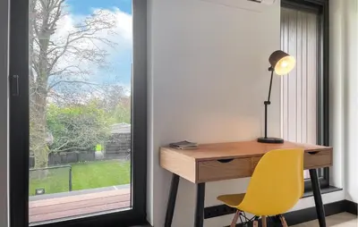 a desk with a lamp and a yellow chair next to a window at Awesome Home In Vinkeveen in Vinkeveen