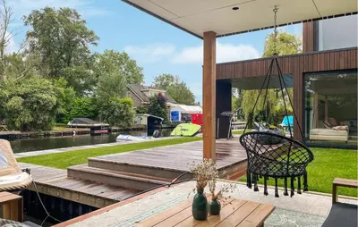 a patio with a swinging chair on a wooden deck at Awesome Home In Vinkeveen in Vinkeveen