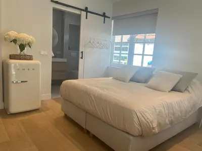 a bedroom with a large bed and a refrigerator at Studio Elysium in Bergen