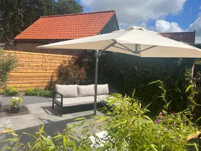 a white umbrella and a chair in a garden at Studio Elysium in Bergen
