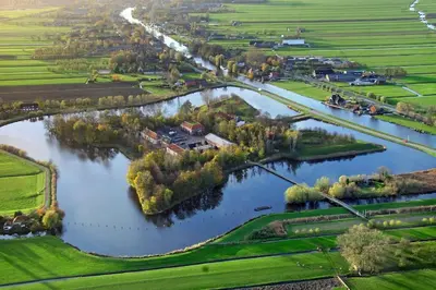 an aerial view of a river with a house and trees at Waterval Wellness-suite met Sauna! in Bodegraven
