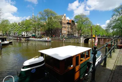 a boat docked in a canal in a city at Tranquil wooden house with free parking in Amsterdam
