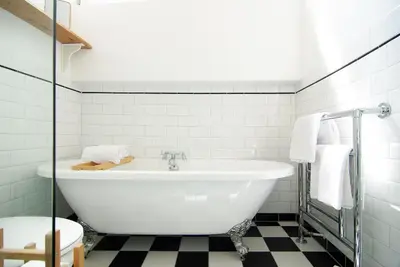 a white bath tub in a bathroom with black and white tiles at Tranquil wooden house with free parking in Amsterdam