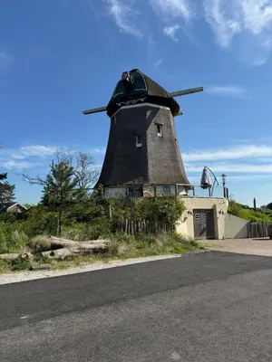 a windmill on the side of a road at In de Duinpan in Egmond aan den Hoef