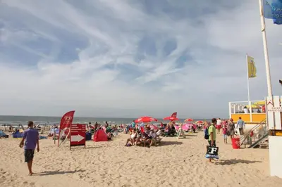 a crowd of people on a beach with umbrellas at In de Duinpan in Egmond aan den Hoef
