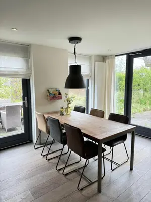 a dining room with a wooden table and chairs at In de Duinpan in Egmond aan den Hoef