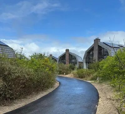 a road in front of two domed buildings with a road at In de Duinpan in Egmond aan den Hoef