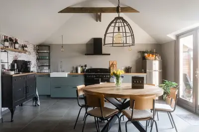 a kitchen with a wooden table and chairs in a kitchen at B&B Hartenlust kamer de Hooizolder in Bodegraven