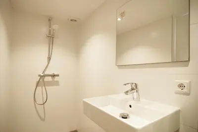 a white bathroom with a sink and a shower at Group Stay, 7 minutes away from Amsterdam! in Halfweg