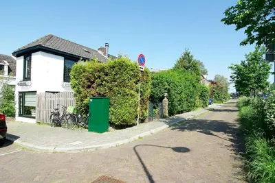 a street with a house and a green trash can at Group Stay, 7 minutes away from Amsterdam! in Halfweg