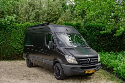 a black van parked in front of some bushes at Mercedes Sprinter Camper FREYA in Heiloo
