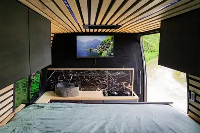 a bedroom in a tiny house with a flat screen tv at Mercedes Sprinter Camper FREYA in Heiloo